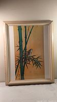 Front view of the framed print showing two sparrows on green bamboo against tan background