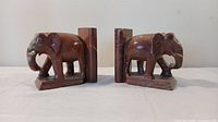 Side view showing detailed carving on both stone elephant bookends with attached vertical back supports.