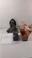 Photo of carved soapstone Buddha with two unused soapstone blocks in boxes and instruction sheet on white surface.