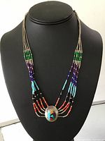 Full view of the multi-strand necklace on black display stand showing full length of bead strands and pendant.