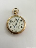 Front view of antique gold filled Elgin pocket watch with white dial and black numerals and hands.