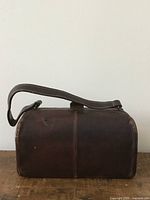 Front view of a dark brown textured leather nurses bag with wear on edges.