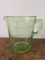 Front side view of the green Depression glass pitcher showing embossed measurement markings for cups and ounces.