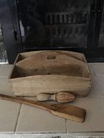 Overall image of wooden tray with dividing board and two wooden accessories in front on tiled floor.