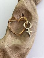 Front view of gilt sterling silver heart brooch with Venus female symbol on natural wood background.