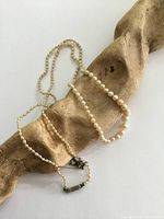 Full-length necklace displayed on driftwood