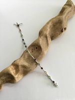 Full view of the bracelet laid on driftwood, showing length and multicolored gemstones.