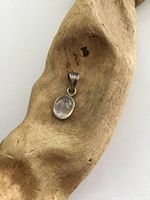 Photo of small drop-shaped moonstone pendant set in sterling silver, showing front view and finish details.