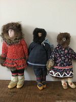 Photo showing full group of three vintage Indigenous dolls in traditional clothing with fur hoods and suede elements.