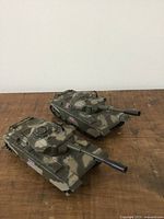Two vintage camouflaged tank models from a side view showing their turrets and details.