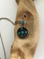 Photo of the vintage sterling silver onyx pendant inset with opals on a wooden display, showing the front view of pendant with five opal insets and the sterling silver chain.