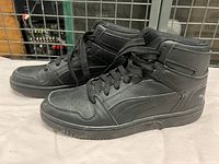 Side view of black Puma high top sneakers showing overall good condition and lace-up design.