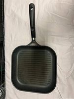 Top view of black square grill pan with ridged surface and black silicone handle.