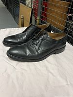 Side view of the pair of men's black leather dress shoes showing the lace-up design and smooth leather finish.