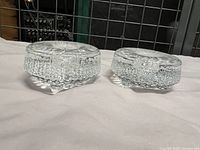 Pair of two clear glass Iittala candle holders with textured melted ice design, side view showing low profile and thickness.