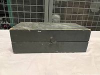 Old wooden shoe shine box closed, showing wear and a latch on the front.