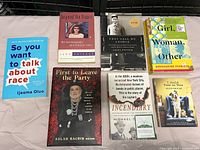 Photo showing 7 assorted books with various topics and colorful covers arranged on a cloth surface.