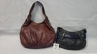 Photo of the two purses together showing the brown leather purse larger on left and black Cole Haan purse on right