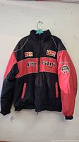 Full front of black and red Ferrari racing jacket with Ferrari, Shell and Marlboro logos on chest and NGK patch on sleeve.