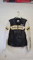 Full front view of black and white leather Harley-Davidson jacket hanging on hanger