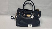 Front view of black Michael Kors leather purse with gold-tone hardware and chain strap