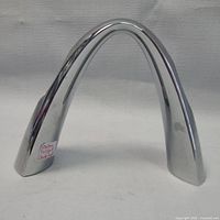 Side view of polished arch-shaped metal candle holder with reflective chrome finish.