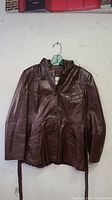 Front view of vintage brown leather jacket showing closure buttons, multiple pockets, and collar.