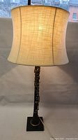 Full view of the clarinet lamp with illuminated fabric shade, showing height and overall styling.