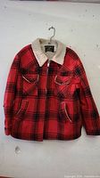 Front view of the red and black plaid jacket with sherpa collar and two chest flap pockets.