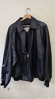 Front view of the Wilsons M. Julian black leather jacket showing zipper and pockets