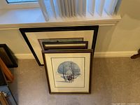 Stacked framed prints leaning against a wall