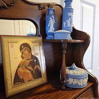 Framed religious icon and blue/white porcelain vases on wooden stand.