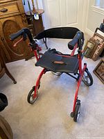 Front view of the red Drive Nitro rolling walker with black seat and backrest, showing the handle grips and wheel design.