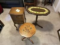 Three small wooden tables grouped together on carpet showing their shapes and decorative tops.