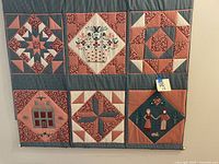 Front view of handmade quilted wall hanging with six square blocks, showing patchwork and applique detail