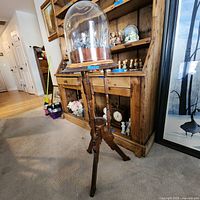 Full view of the wooden tripod stand with glass dome cover on top