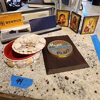 Full view of all items including the Benrus watch in box, shell-decorated jewelry box, three framed religious pictures, and wooden plaque with peace message.