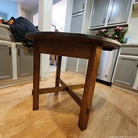 Photo of the round wooden kitchen table showing the tabletop and legs, highlighting the wood grain and wear.