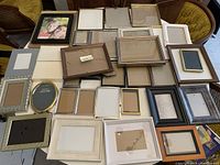 Wide view of various small empty picture frames of different sizes and styles arranged on a surface
