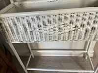 Side angled view showing the white wicker exterior and bottom support bar.