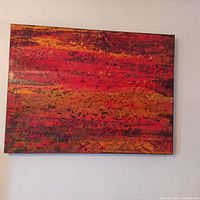 Front view of abstract painting in gold, red and orange tones hung on wall