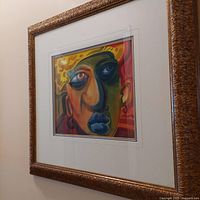 Photo showing framed original abstract face print artwork with a heavily matted white border and ornate brown textured frame.