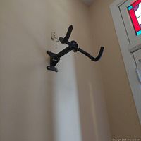 Side angle view of the black steel bike mount on a wall showing padded hooks and mounting plate.