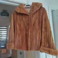 Front view of the reddish-brown fox fur coat showing large cuffs and wide collar, hanging on a hanger.