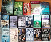 Top view of 19 mixed softcover and hardcover mystery books including multiple Anne Perry titles and some other authors