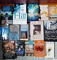 Photo of 12 British mystery books by noted authors, arranged in three rows on carpeted floor showing titles and covers.