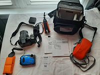 Full lot showing Nikon Coolpix P510, Fujifilm XP camera, Lowepro bag, batteries, charger, wrist strap, manual