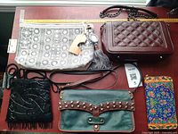 Top view of four purses and wallets all laid out on surface showcasing variety of colors and styles.
