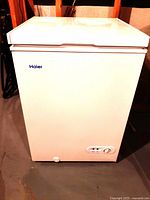 Front view of the white Haier chest freezer, showing control knob and indicator lights.