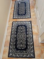 Two matching blue area mats placed on tile floor showing full pattern and size.